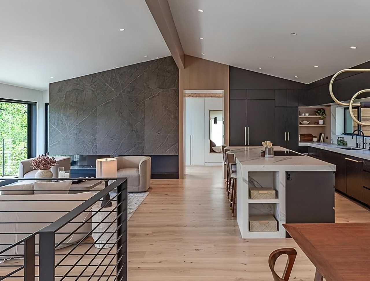 Open kitchen with waterfall island and stone fireplace wall